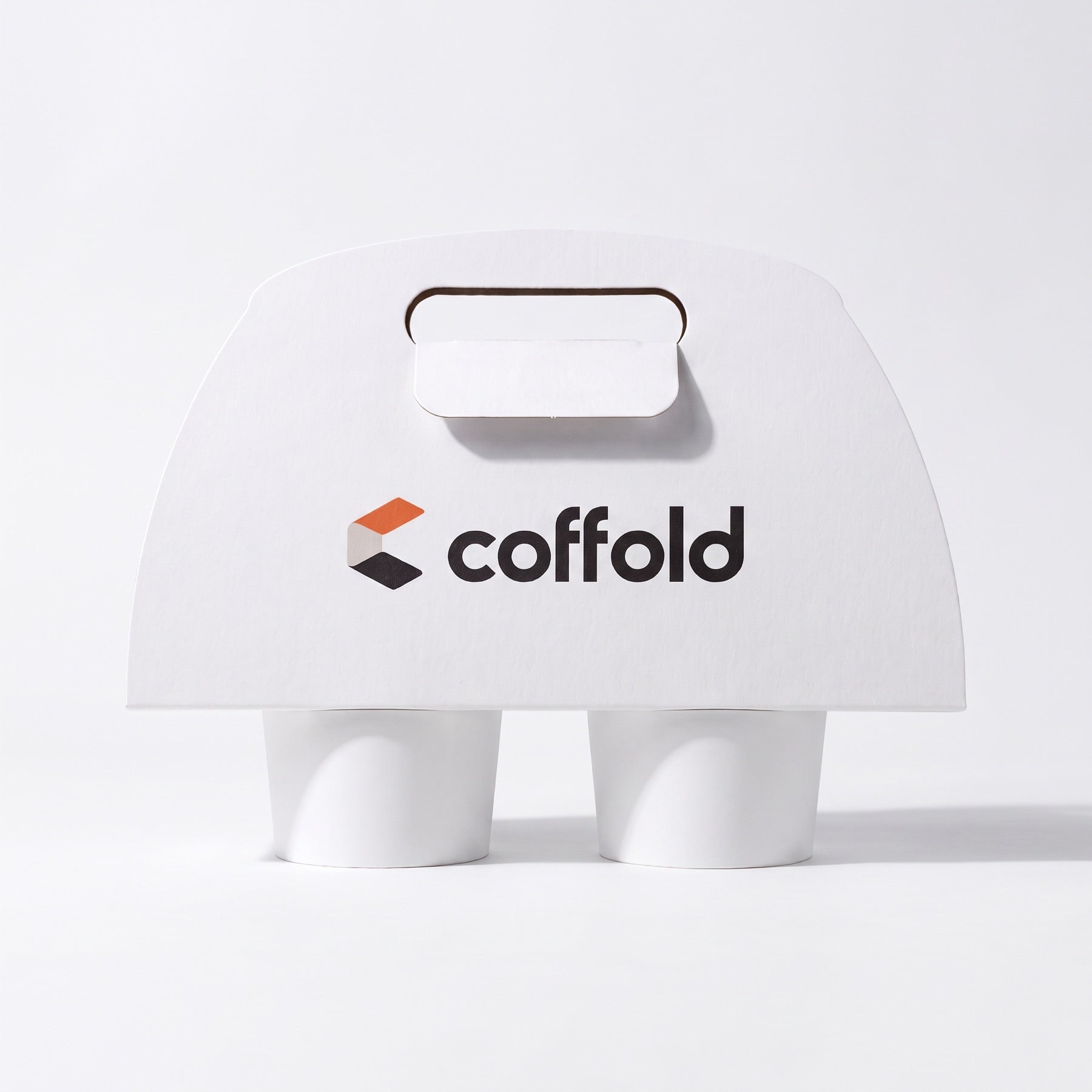 Coffold two-cup drinks carrier in white board, locking tab folded through the handle slot, holding two takeaway coffee cups