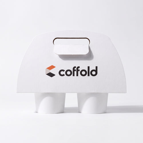 Coffold two-cup drinks carrier in white board, locking tab folded through the handle slot, holding two takeaway coffee cups